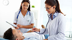 Two female doctors investigating a young, male pacient Two female doctors investigating a young, male pacient