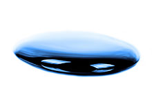 Close-up of a liquid drop on a white surface Close-up of a dark blue,liquid, drop on a white surface