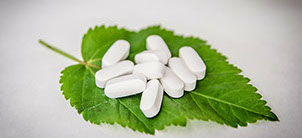 Image of a group of white pills on a green leaf Image of a group of white pills on a green leaf