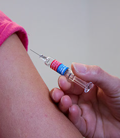 Close-up of a vaccination scene, with a seringe and a skin detail of the arm of a patient Close-up of a vaccination scene, with a seringe and a skin detail of the arm of a patient
